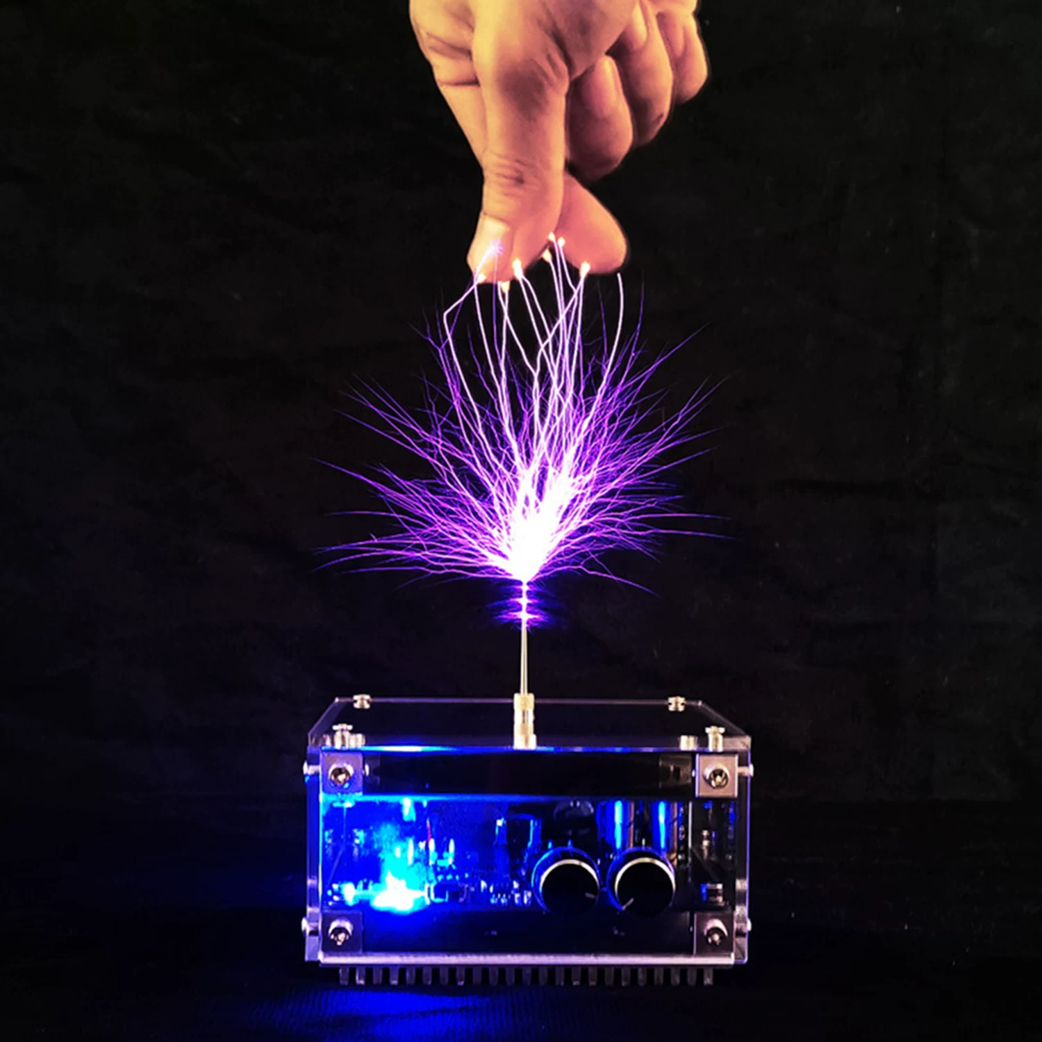 PPK-TSMINI Bluetooth Music Tesla Coil — PPK-TSMINI illuminated in blue with branching purple arcs above the discharge needle and a hand visible overhead.