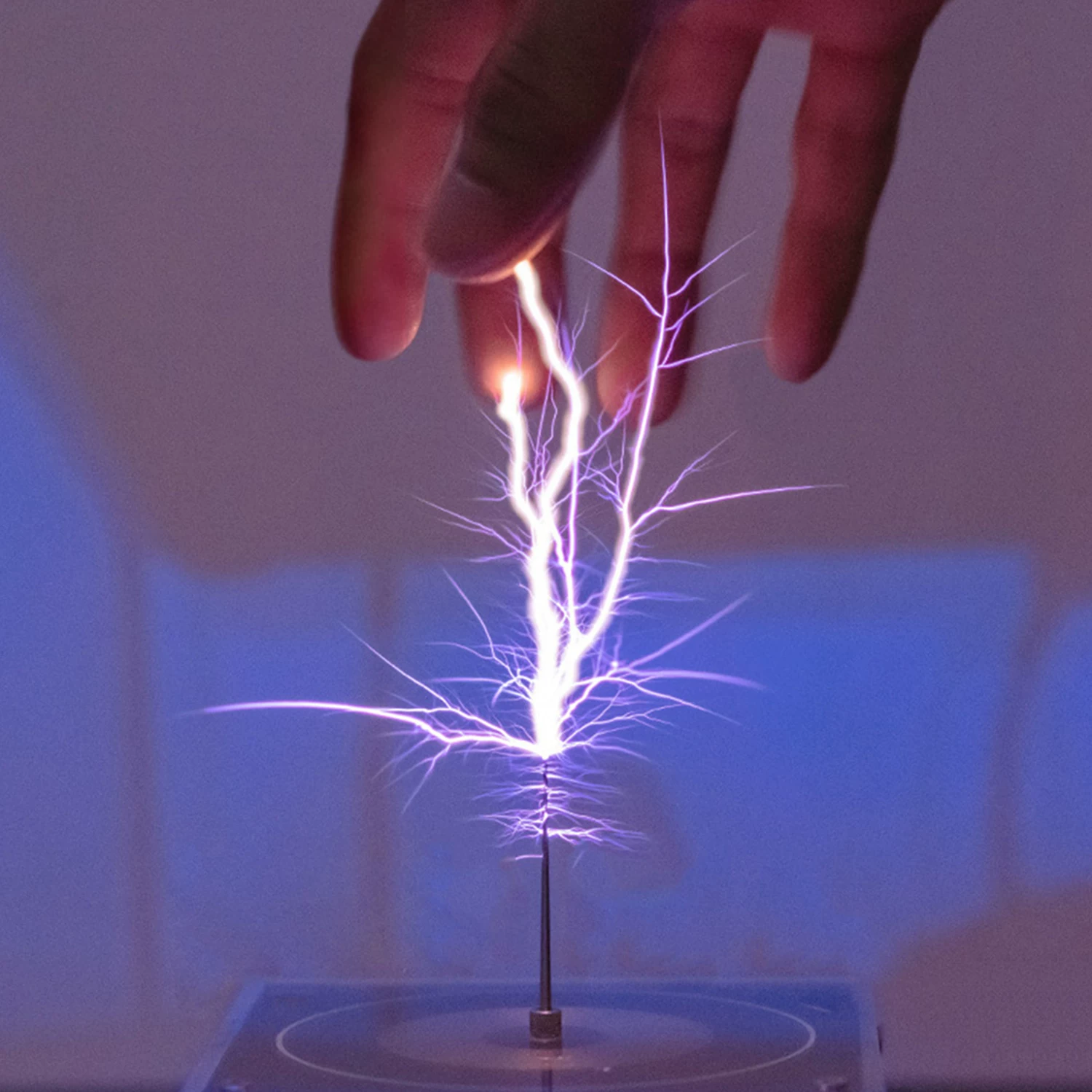 PPK-TSMINI Bluetooth Music Tesla Coil — Close-up source photograph of purple electrical arcs above the PPK-TSMINI discharge needle with a hand visible overhead.